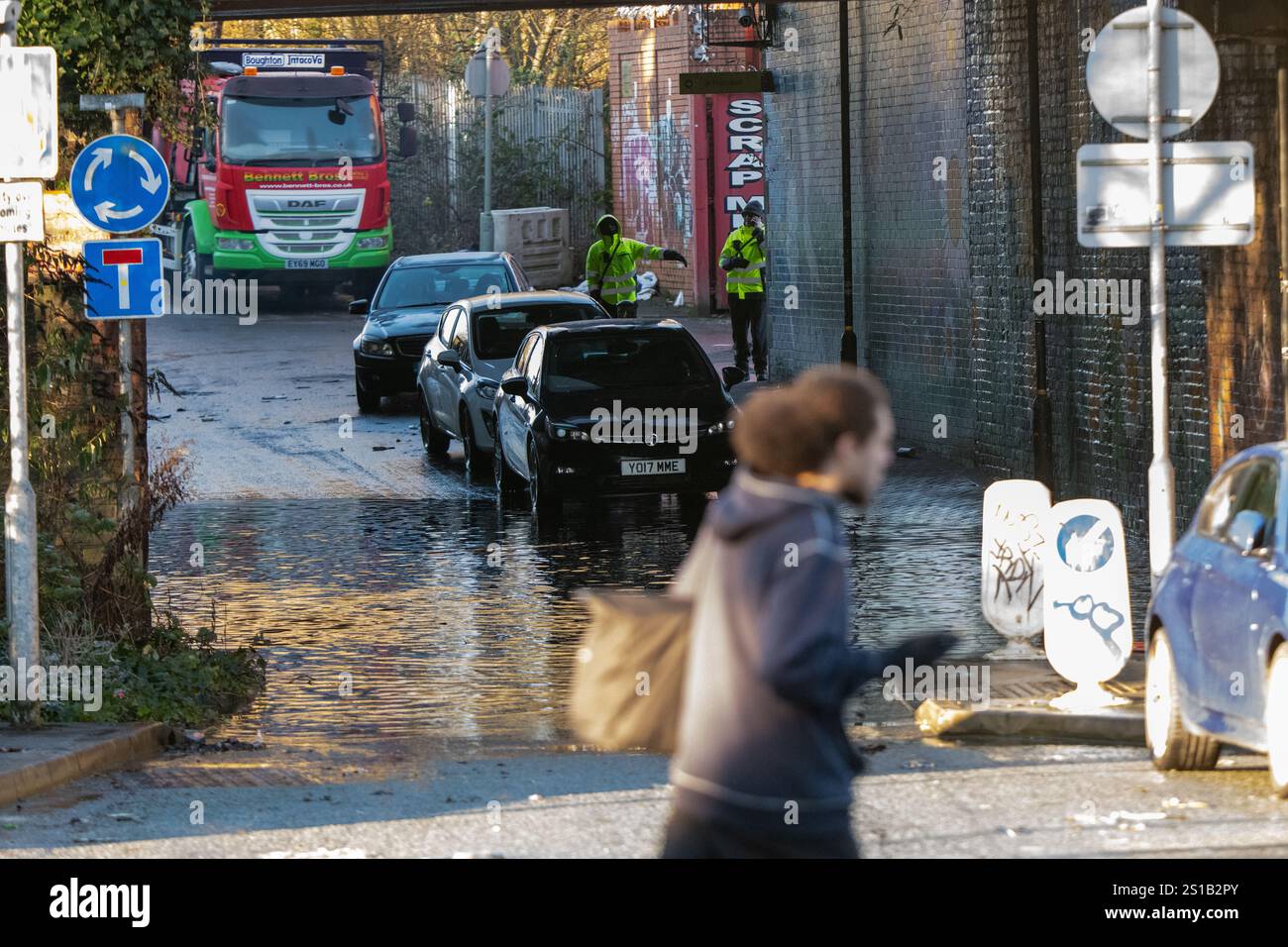 Blockierter Zugang zur Cornbrook Tram Haltestelle Manchester. Die Aufräumarbeiten beginnen nach einer starken Überschwemmung in South Manchester, nachdem zu Beginn des neuen Jahres heftige Regenfälle stattgefunden hatten. Der Platz wurde vollständig mit Wasser und Schmutz überflutet, die die Grünflächen mit Fahnen bedeckten. Das Clubhaus ist komplett von Wasser umgeben. Der nahe gelegene Fletcher Moss Park and Gardens ist komplett überflutet mit Parkbänken und Parkinformationsschildern. Die Umweltbehörde pumpte Wasser und errichtete Hochwasserbarrieren zum Schutz in der Nähe Stockfoto