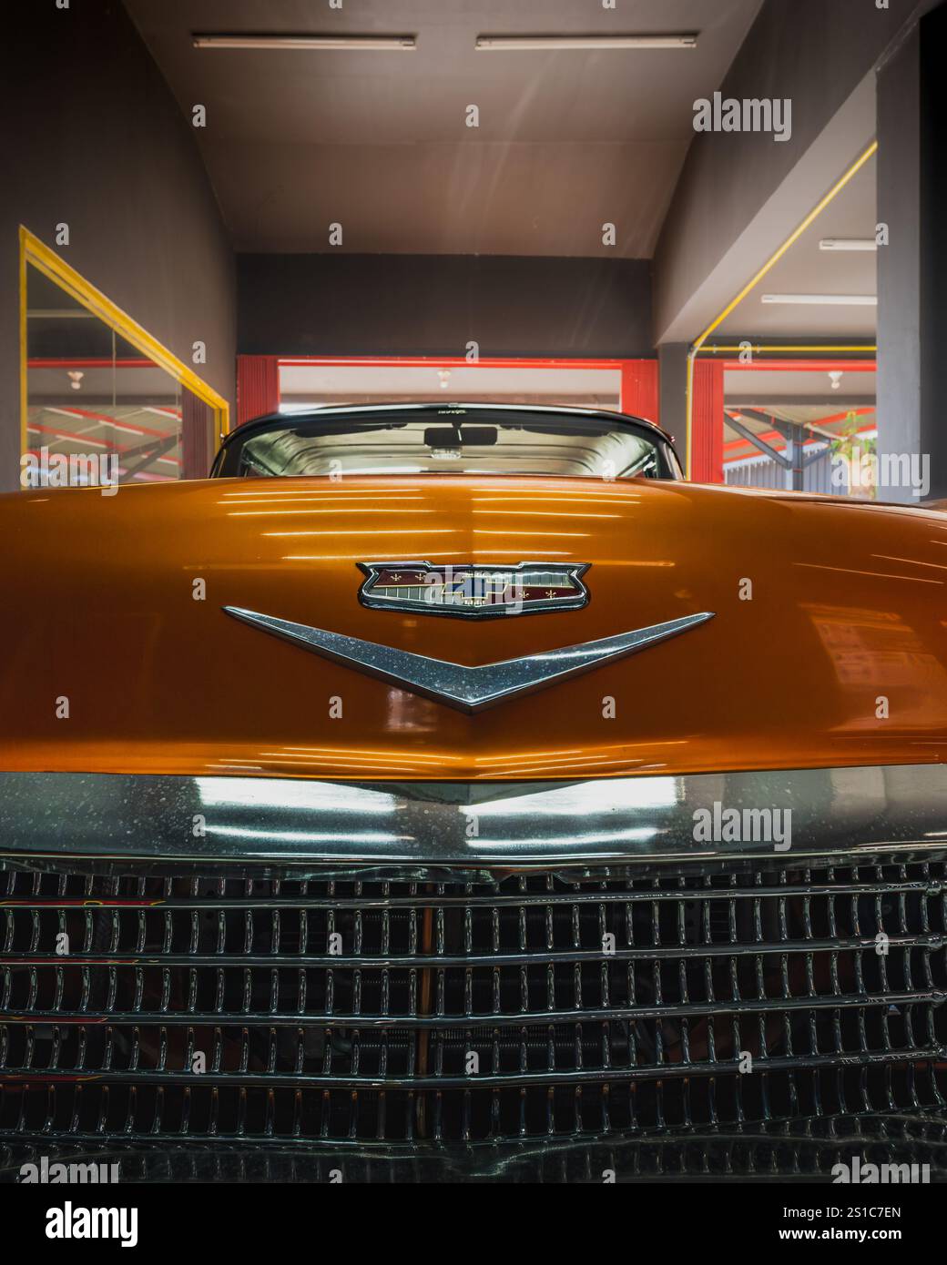 Balikpapan, Indonesien - 18. Dezember 2024. Nahaufnahme der Vorderseite eines Oldtimer 1958 Chevrolet Impala orange mit Chromdetails Stockfoto