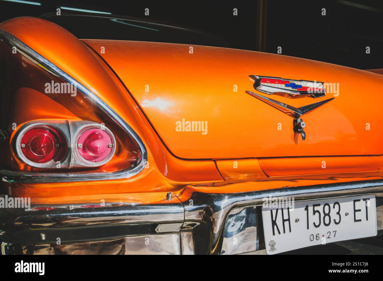 Balikpapan, Indonesien - 18. Dezember 2024. Nahaufnahme des Hecks eines orangen Oldtimers mit Chromdetails, Rückleuchten und Chevr Stockfoto