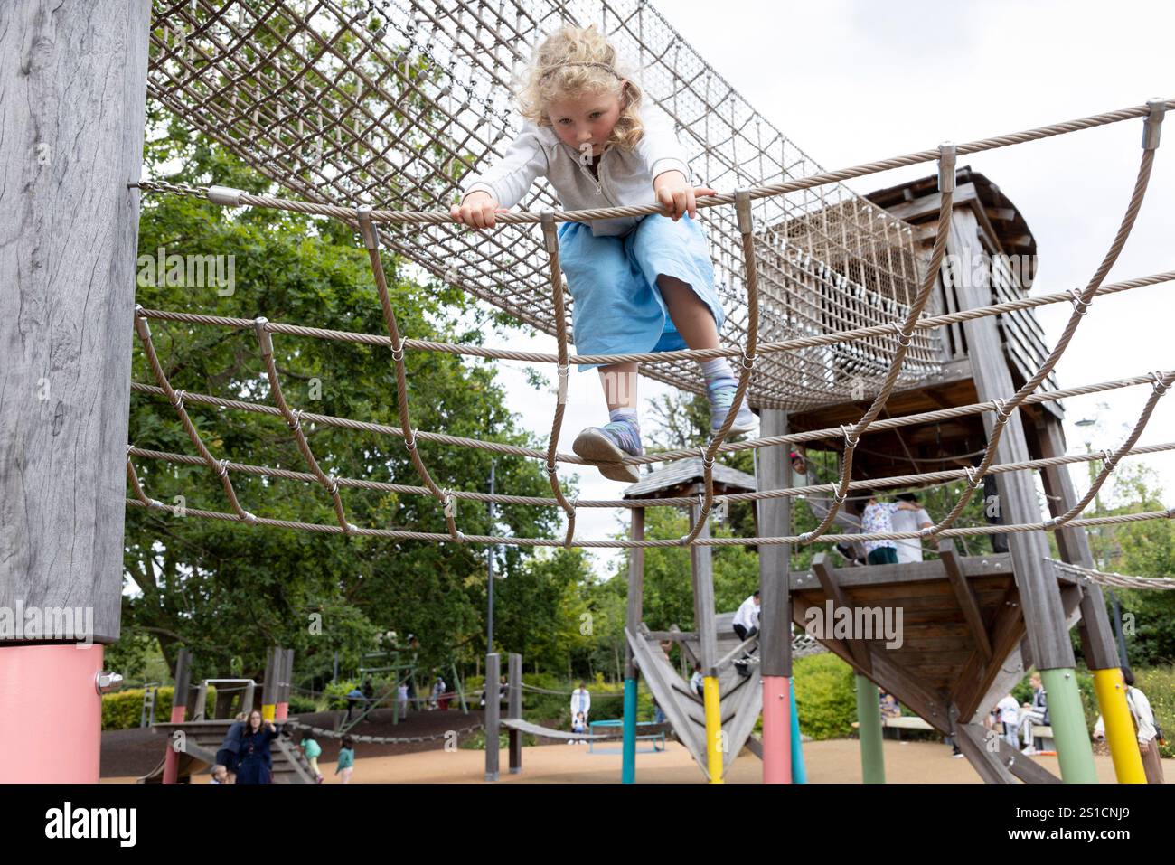 Ein 7-jähriges weißes Mädchen klettert auf einem Spielplatz in Brent Cross Town (einer Neubauanlage), London Stockfoto