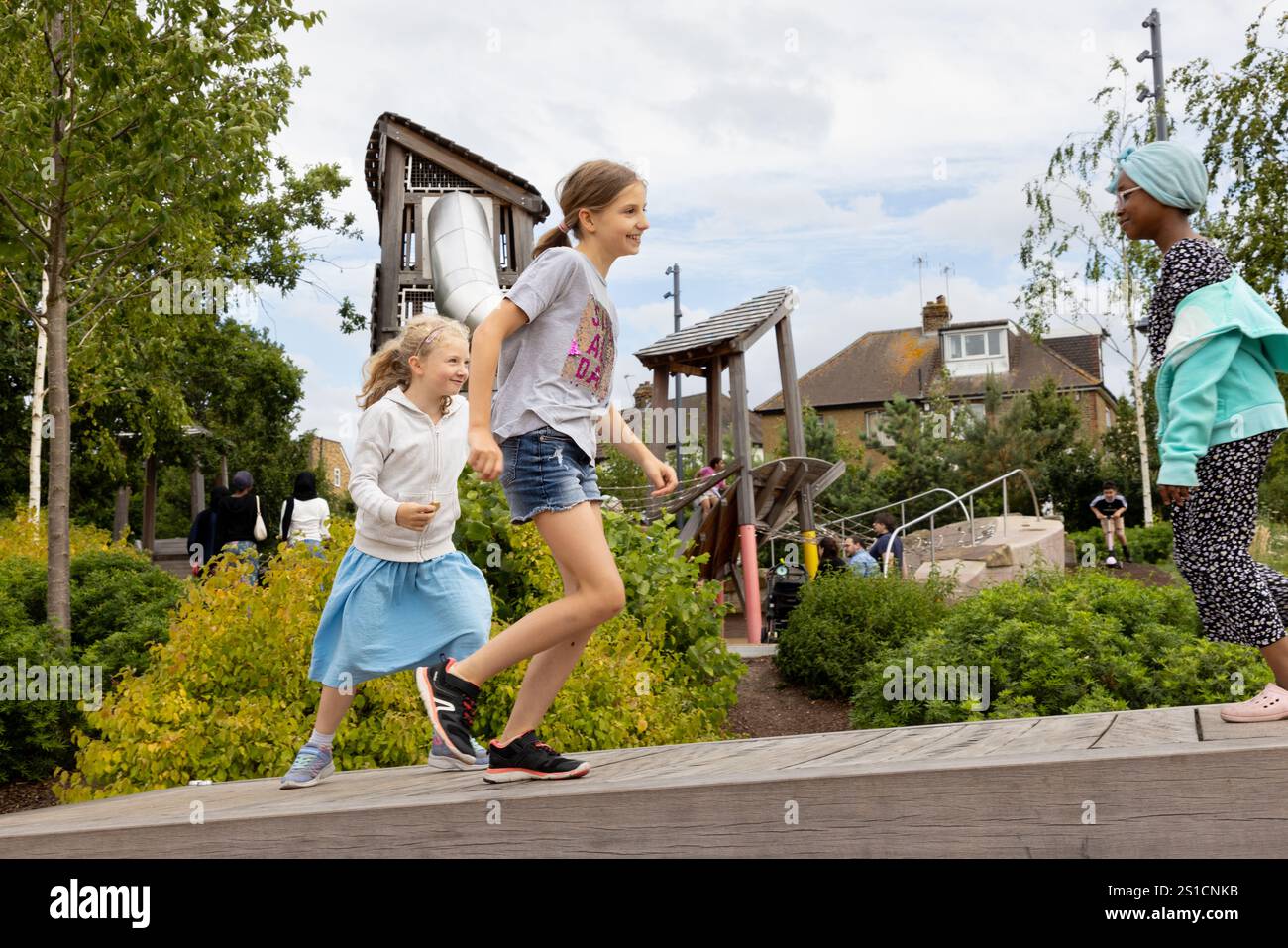 Drei Kinder spielen auf einer begehbaren Seesäge auf einem Spielplatz in Brent Cross Town, einem Baugebiet in NW London. Sie haben Spaß und erkunden das Gleichgewicht. Stockfoto