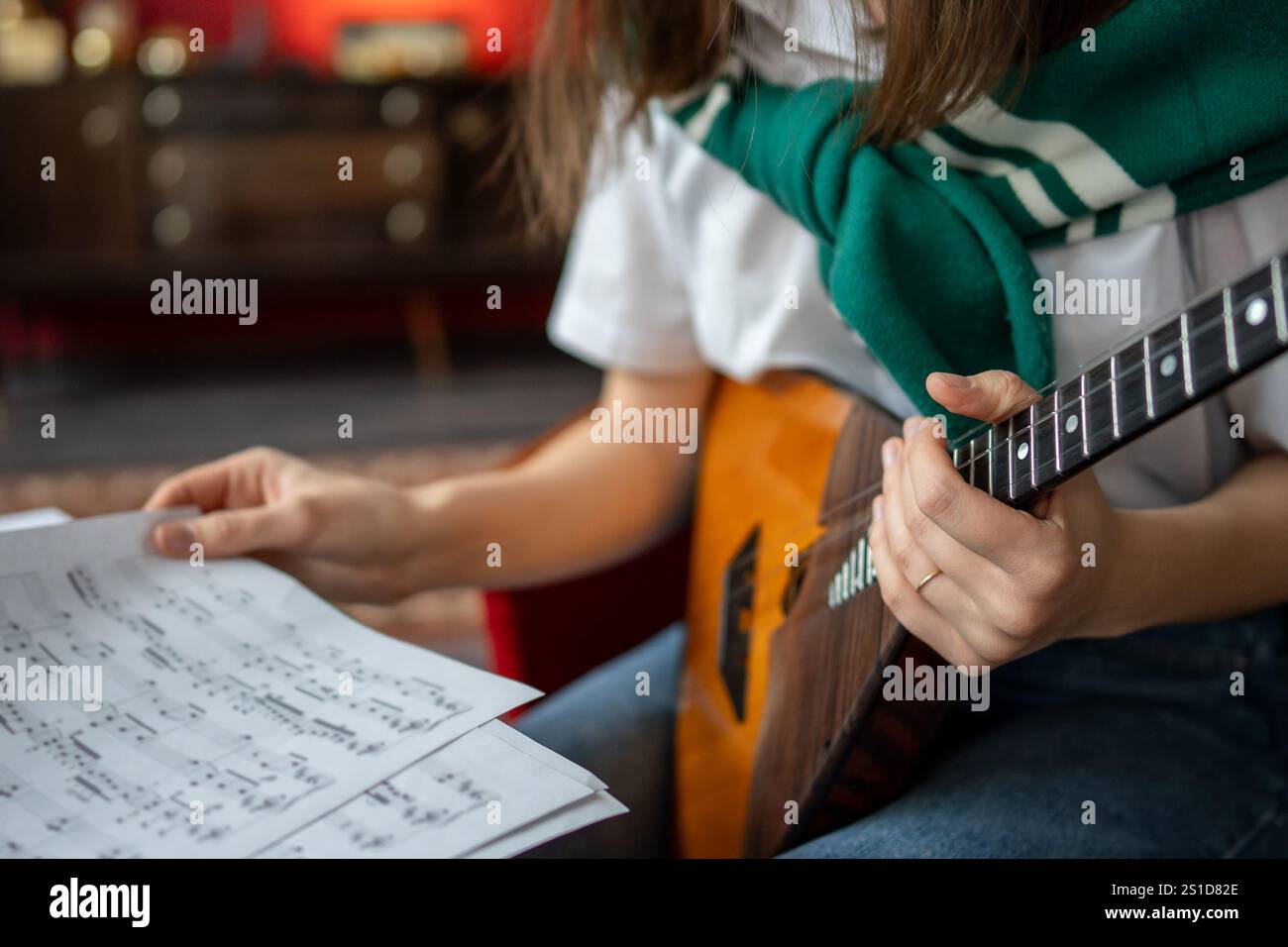 Musikstudentin untersucht Balalaika-Noten und Akkorde und plant Übungssitzungen zu Hause oder im Unterricht Stockfoto