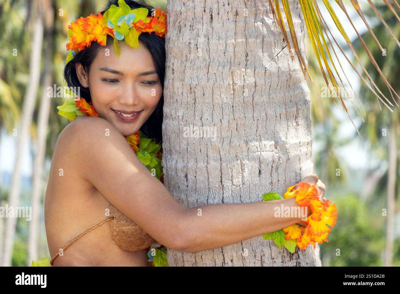 Hula-Hawaii-Tänzerin umarmt eine Kokospalme Stockfoto