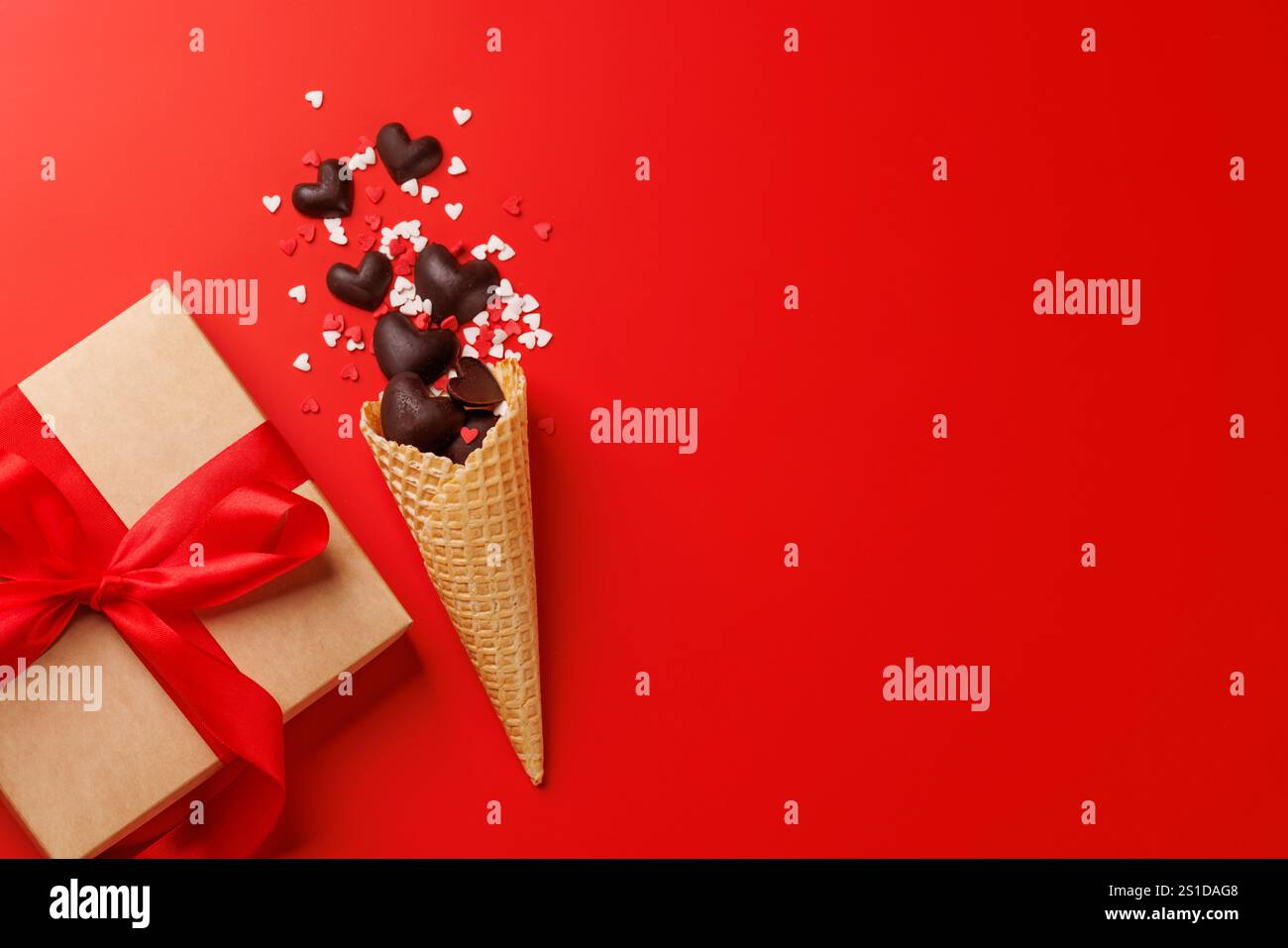 Eine bezaubernde Kombination aus herzförmigen Süßigkeiten in einer Eiskegel, kombiniert mit einer Valentinstag-Geschenkbox, die ein perfektes Geschenk für jemanden ist Stockfoto