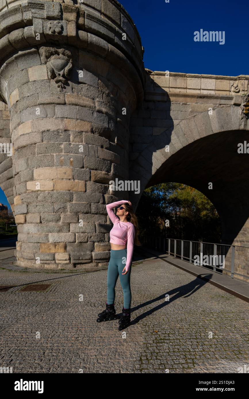 Sportliche Frau, die Inline-Skates trägt, posiert an einem sonnigen Tag unter einem Brückenbogen Stockfoto