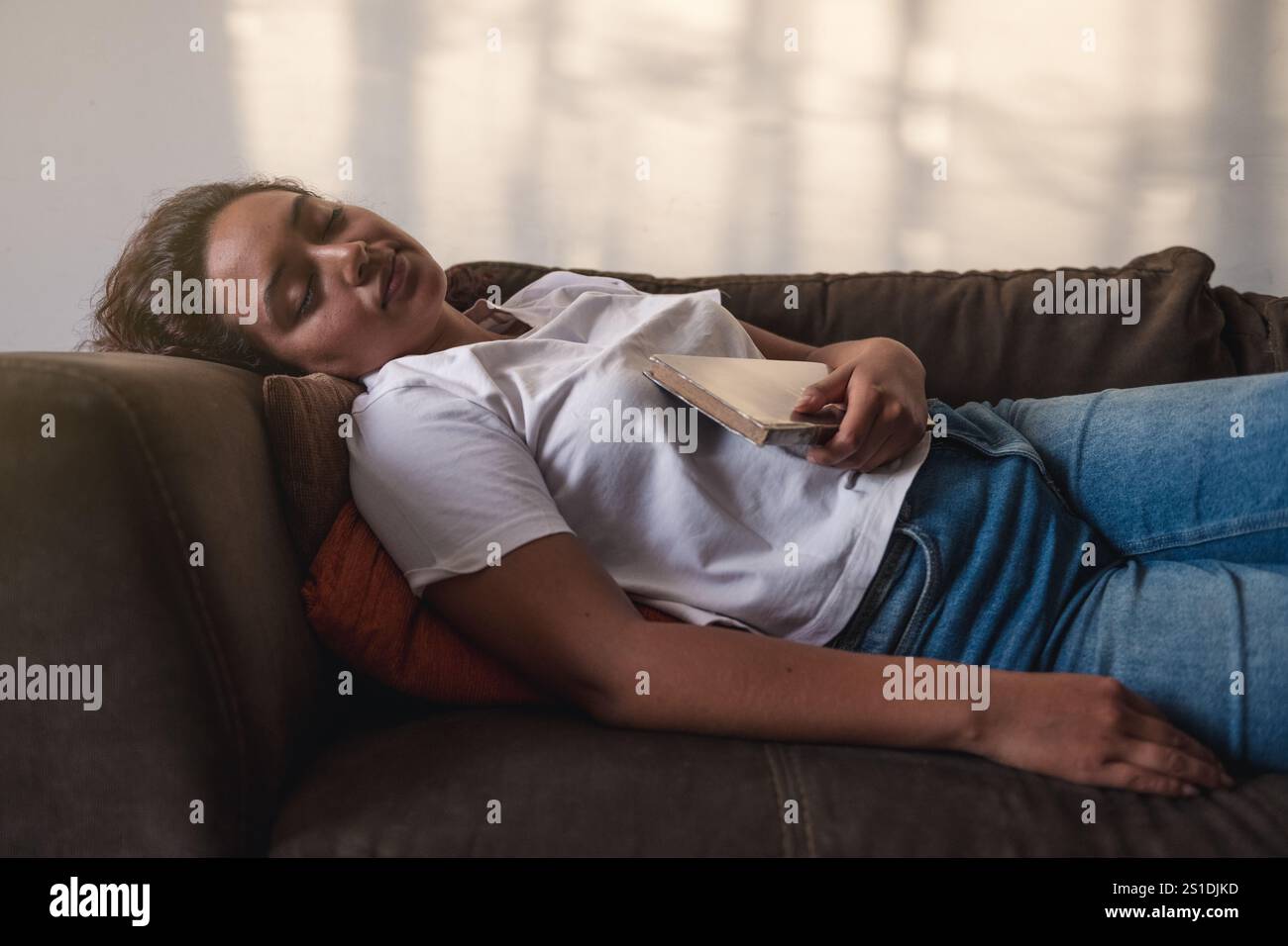 Hübsche Frau, die auf dem Sofa in ihrem Wohnzimmer schläft, nachdem sie ein Buch veröffentlicht hat Stockfoto