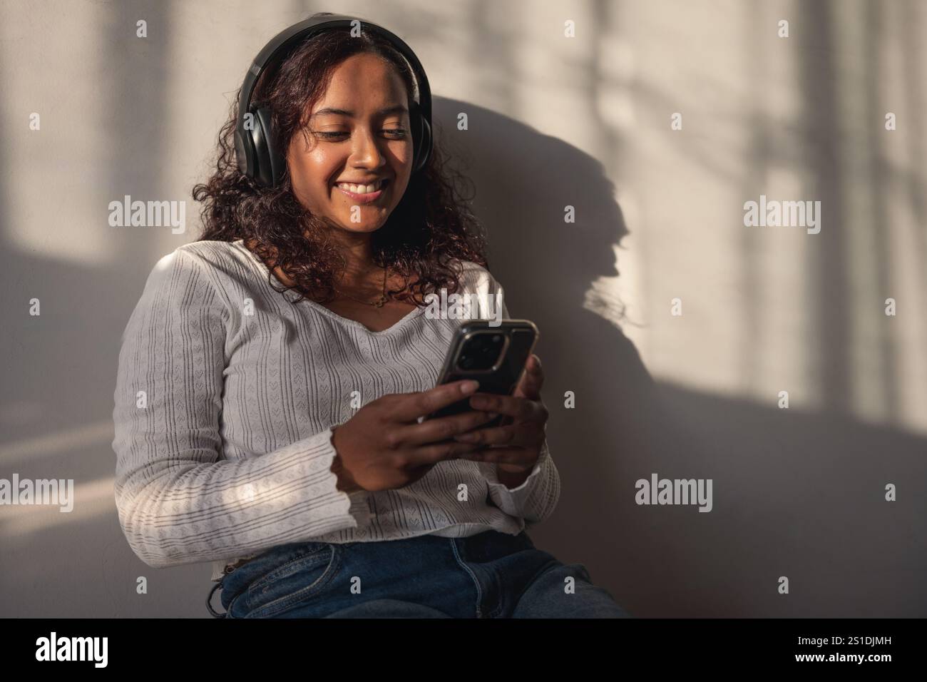 Junge Frau, die Kopfhörer hört und ein Smartphone ansieht Stockfoto