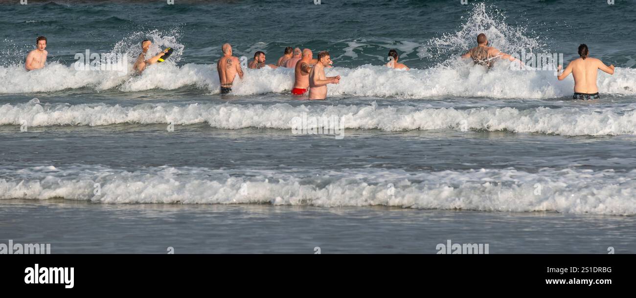 Ein Panoramabild einer Gruppe männlicher Kaltwasserschwimmer, die am frühen Morgen am Towan Beach in Newquay Cornwall, Großbritannien, ins Meer waten. Stockfoto