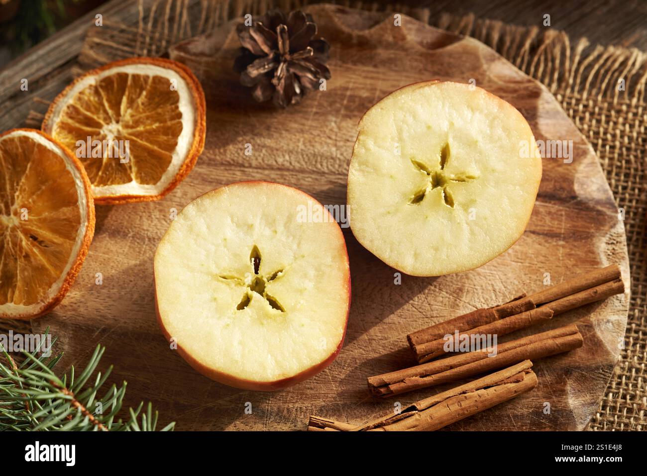 Halbierter Apfel mit einem Stern in der Mitte, mit Gewürzen und Weihnachtsdekoration Stockfoto