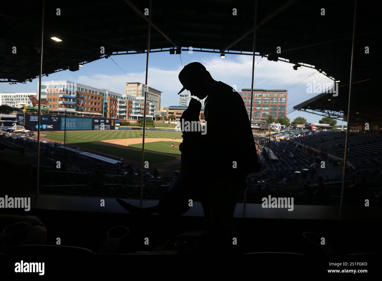 Durham, North Carolina, USA. Januar 2025. Michael O'Donnell aus Raleigh mit seinem Hund Ripken, dem Fledermaushund im Klubhaus im Durham Bulls Stadium. Ripken, der Fledermaushund, der unendlich eifrige schwarze Labrador, der bei den Durham Bulls und der N.C. State University die Herzen gestohlen hat, ist unerwartet gestorben. Die O'Donnell-Familie, die Ripken ausgebildet hat, kündigte am Freitag seinen Tod an, weil Komplikationen aufgrund eines nicht diagnostizierten Krankheitszustandes entstanden sind. Er war 8 ''" ein Anspielung auf die Nummer seines Namensvetters für die Baltimore Orioles. Foto vom 23.07.22. (Credit Image: © Bob Karp/ZUMA Press Wire) NUR REDAKTIONELLE VERWENDUNG! Keine Gutschrift: Stockfoto