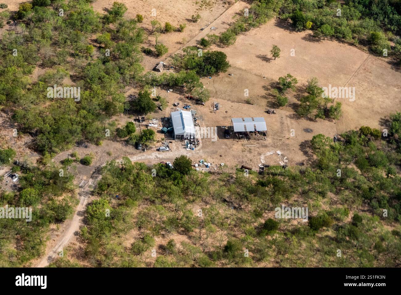 Austin, Texas – aus der Vogelperspektive auf einen Autohafen und einen Lagerhallen am Stadtrand von Austin Texas mit einem verlassenen Auto und Trümmern, die um den Hof verstreut sind Stockfoto