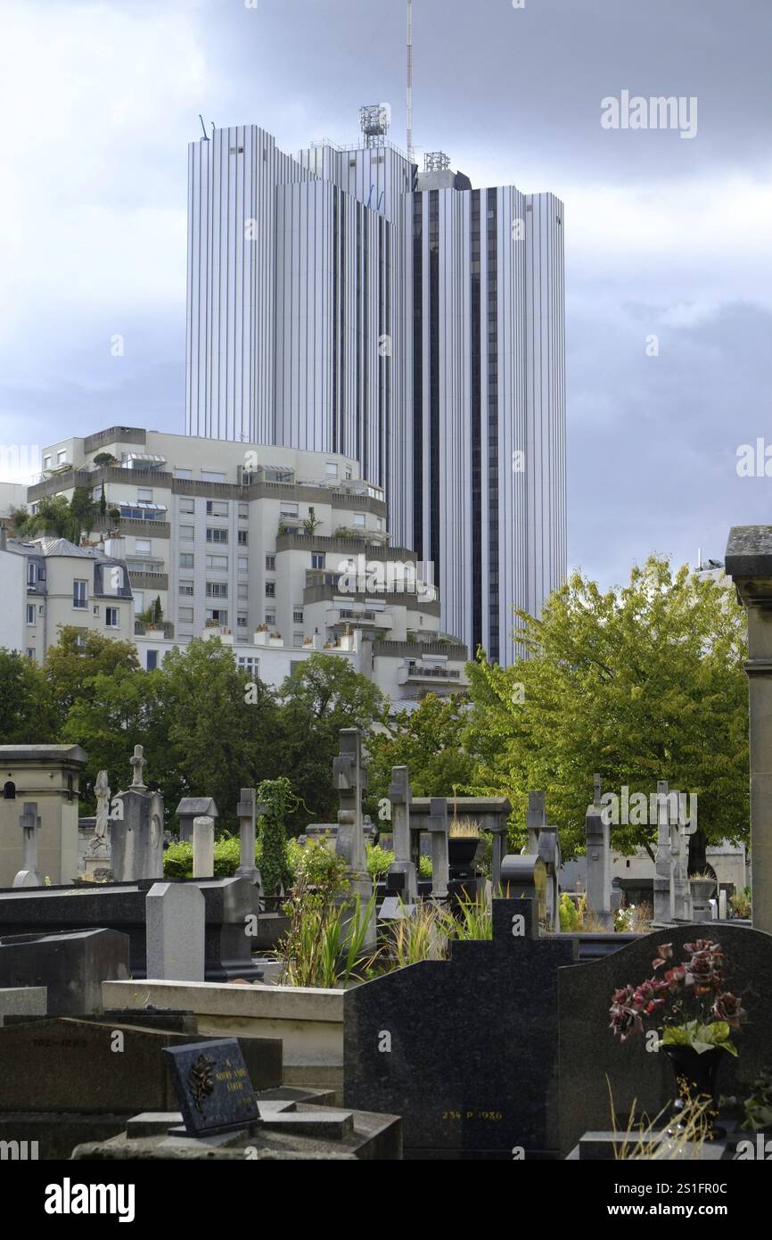 Gräber und Grabsteine auf dem Friedhof Cimetiere Montparnasse in Paris, einem Turmblock im Hintergrund. Hochformat. Gräber und Grabsteine bei t Stockfoto