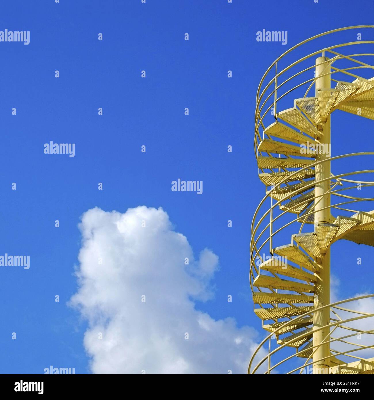 Hellgelb lackierte Wendeltreppe vor einem stahlblauen Himmel. Quadratisches Format. Hellgelb lackierte Wendeltreppe gegen ein Ross Stockfoto