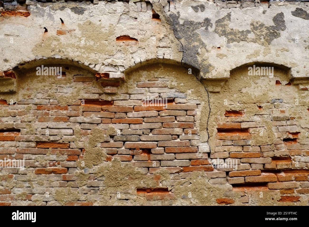 Alte Ziegelmauer mit Rundbögen und ausgebrochenen Steinen. Querformat. Alte Ziegelmauer mit Rundbögen und ausgebrochenen Ziegeln. Horizontales Format Stockfoto