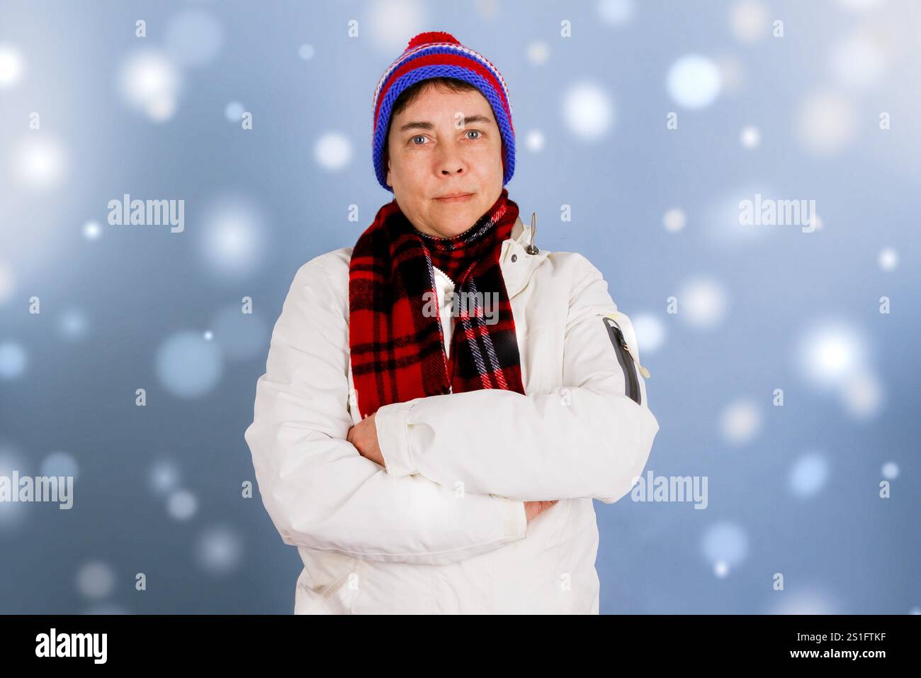 Frau mit gefalteten Armen in Winterkleidung mit Schneeflocken Stockfoto