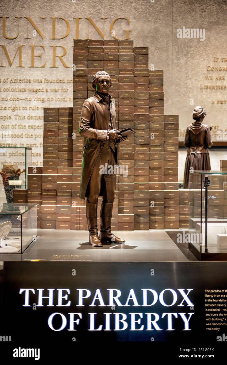 WASHINGTON DC, USA – Eine Statue von Thomas Jefferson steht hinter einem Schild mit der Aufschrift „The Paradox of Liberty“ im National Museum of African American History and Culture. Die Ausstellung untersucht den Widerspruch zwischen Jeffersons Worten über Freiheit und seinem Besitz an versklavten Menschen. Die Ausstellung ist Teil der permanenten Sammlung des Museums, die die frühe amerikanische Geschichte untersucht. Stockfoto