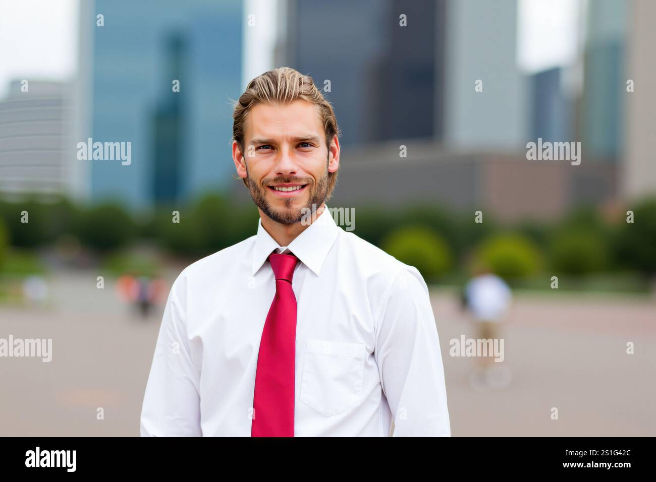 Junger Manager, der selbstbewusst vor modernen Wolkenkratzern im Geschäftsviertel La Défense lächelt und die pulsierende Stadtlandschaft von Paris zeigt, Stockfoto