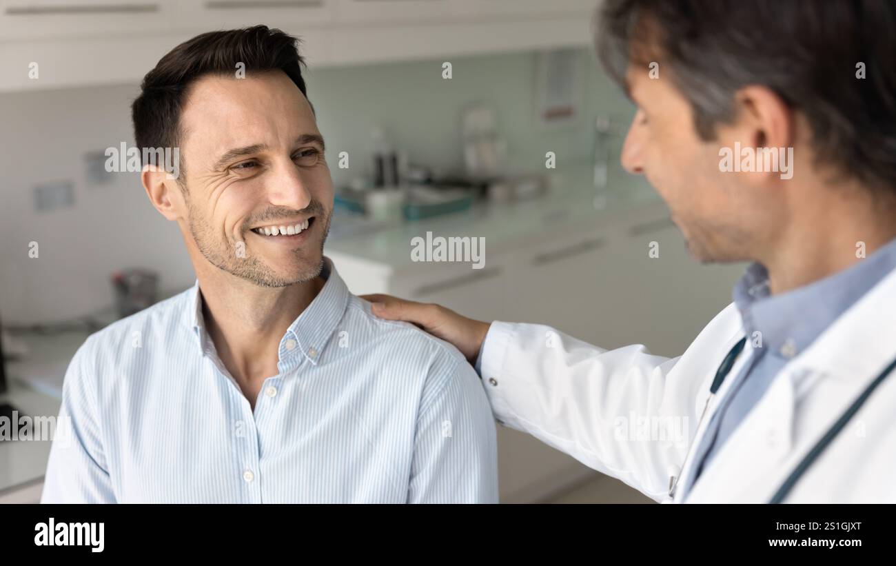 Glücklicher männlicher Patient, der Unterstützung bekommt, gute Nachrichten vom Arzt Stockfoto