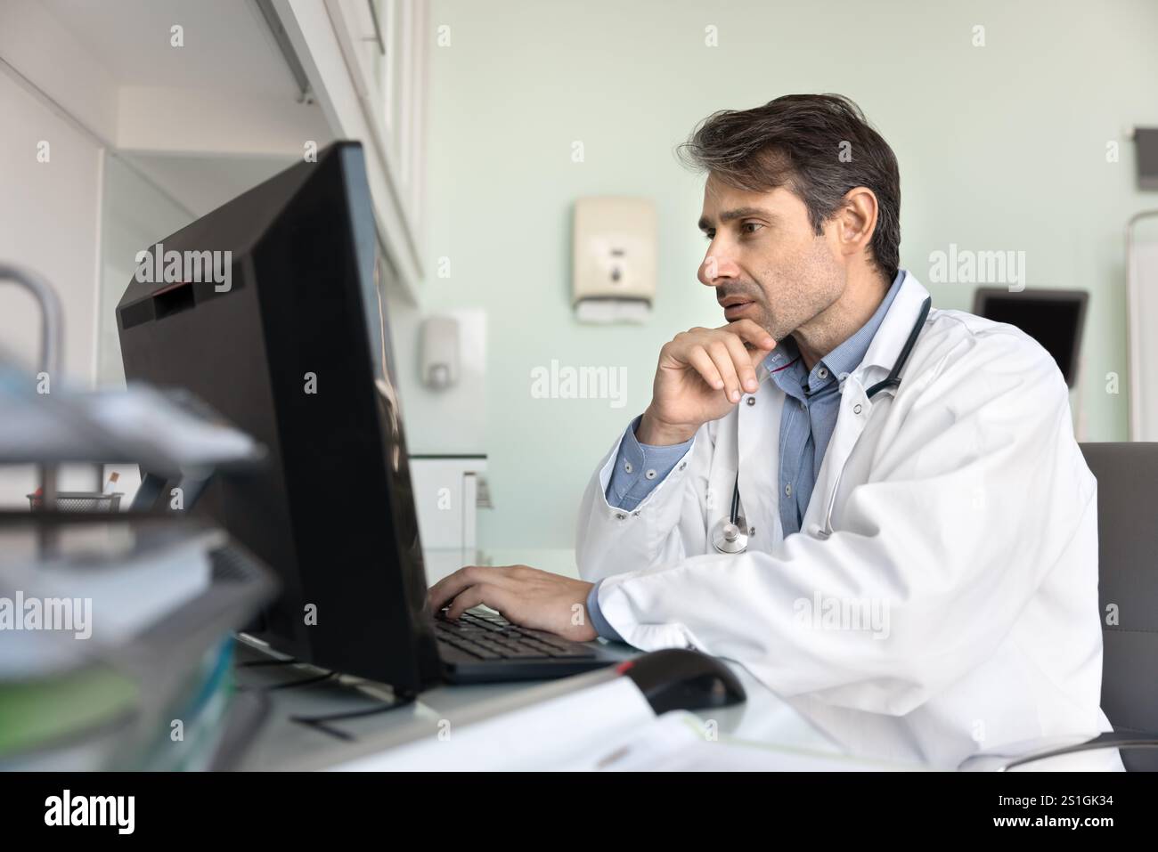 Fokussierter Arzt, der am Desktop in der Krankenhauspraxis arbeitet Stockfoto