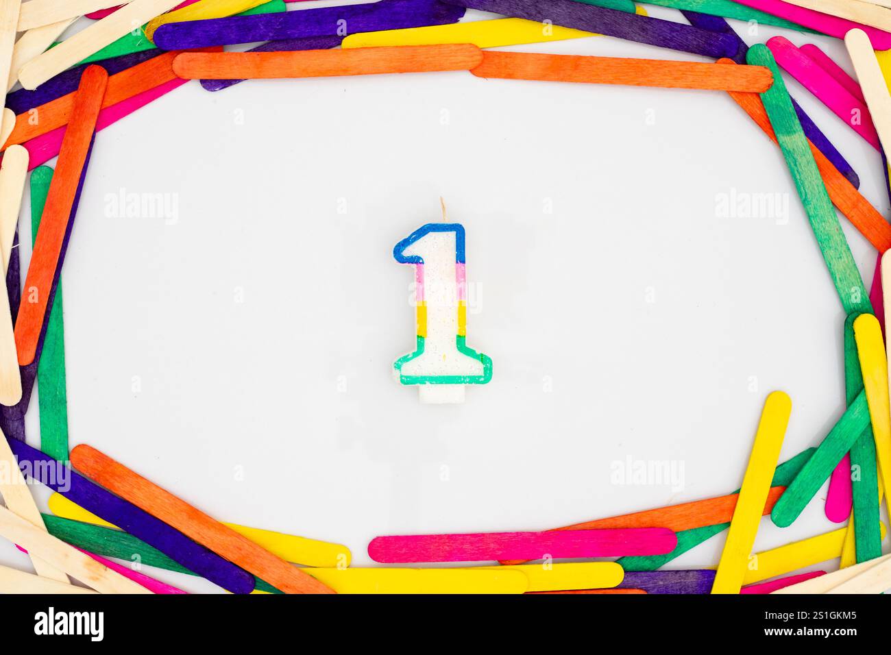 Regenbogenförmige Kerze Nummer eins mit farbenfrohen Sticks Hintergrund Stockfoto