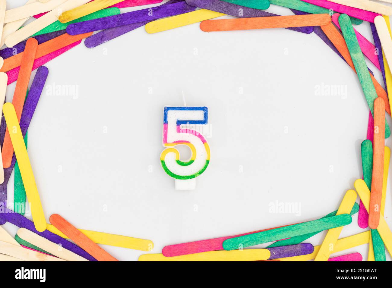 Kerze Nummer 5 mit bunten Stäben auf weißem isoliertem Hintergrund Stockfoto