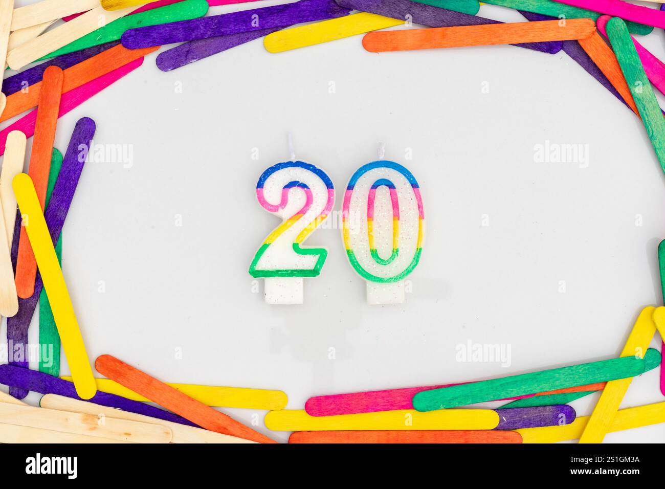 Farbenfrohe Zahl 20-förmige Kerze mit Eis-Sticks Hintergrund Stockfoto