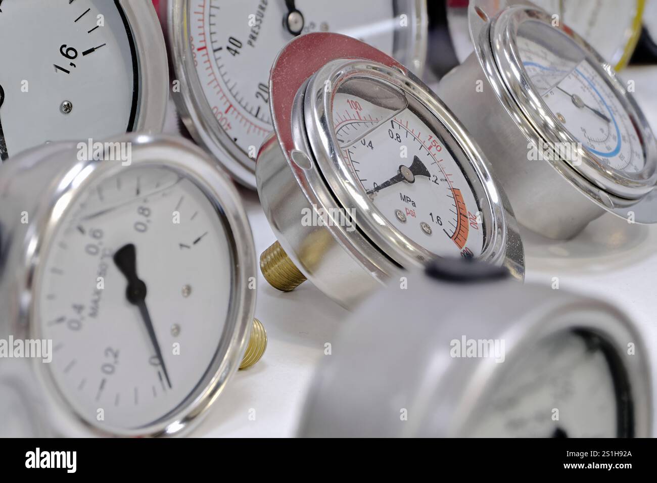 Gruppe mehrerer mechanischer Temperatur- und Manometer. Nahaufnahme, selektiver Fokus, abstrakter Technologiehintergrund. Stockfoto