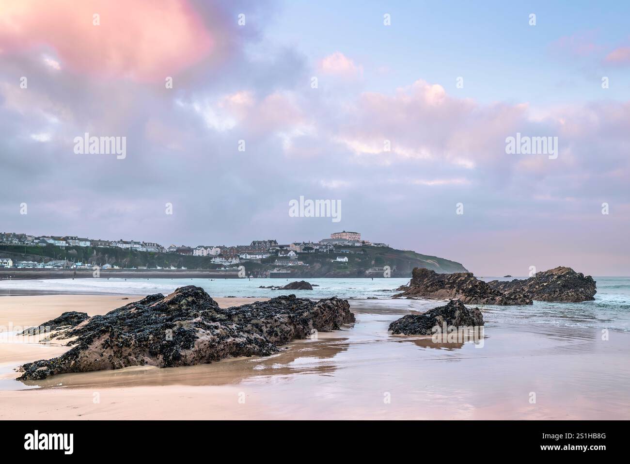 Pastellfarbener Himmel über Felsen, die von Ebbe am GT Western Beach an der Küste von Newquay in Cornwall in Großbritannien freigelegt werden. Stockfoto