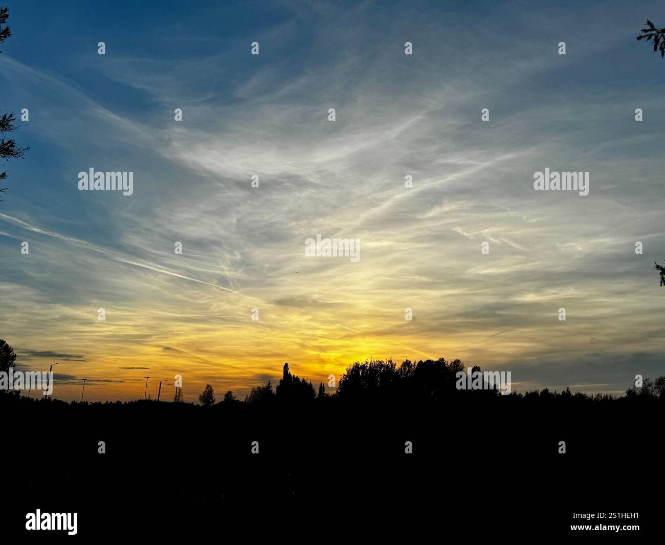Goldener Sonnenuntergang mit dramatischen Wolken über der finnischen Landschaft, ein ruhiger Abschluss eines Herbsttages - Smartphone-aufgenommenes Stockfoto