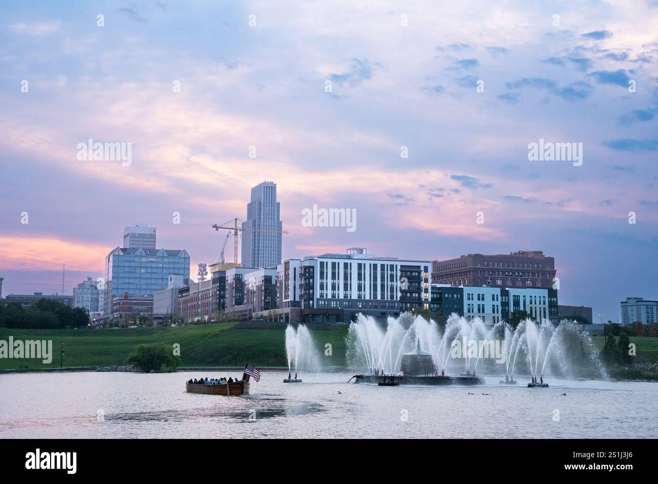 Blick auf die Skyline von Omaha Nebraska bei Sonnenuntergang vom Heartland of America Riverside Park aus mit Blick auf den See. Stockfoto