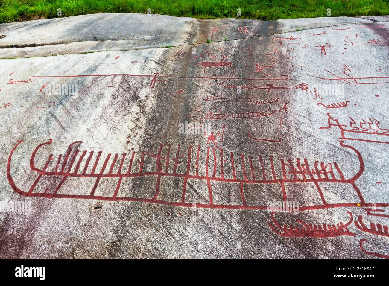 Die Rote Malerei der Tanum-Felsritzereien auf dem Vitlycke-Flachfelsen zeigt Boote, Menschen und Tiere aus der Bronze- und Eisenzeit. Stockfoto