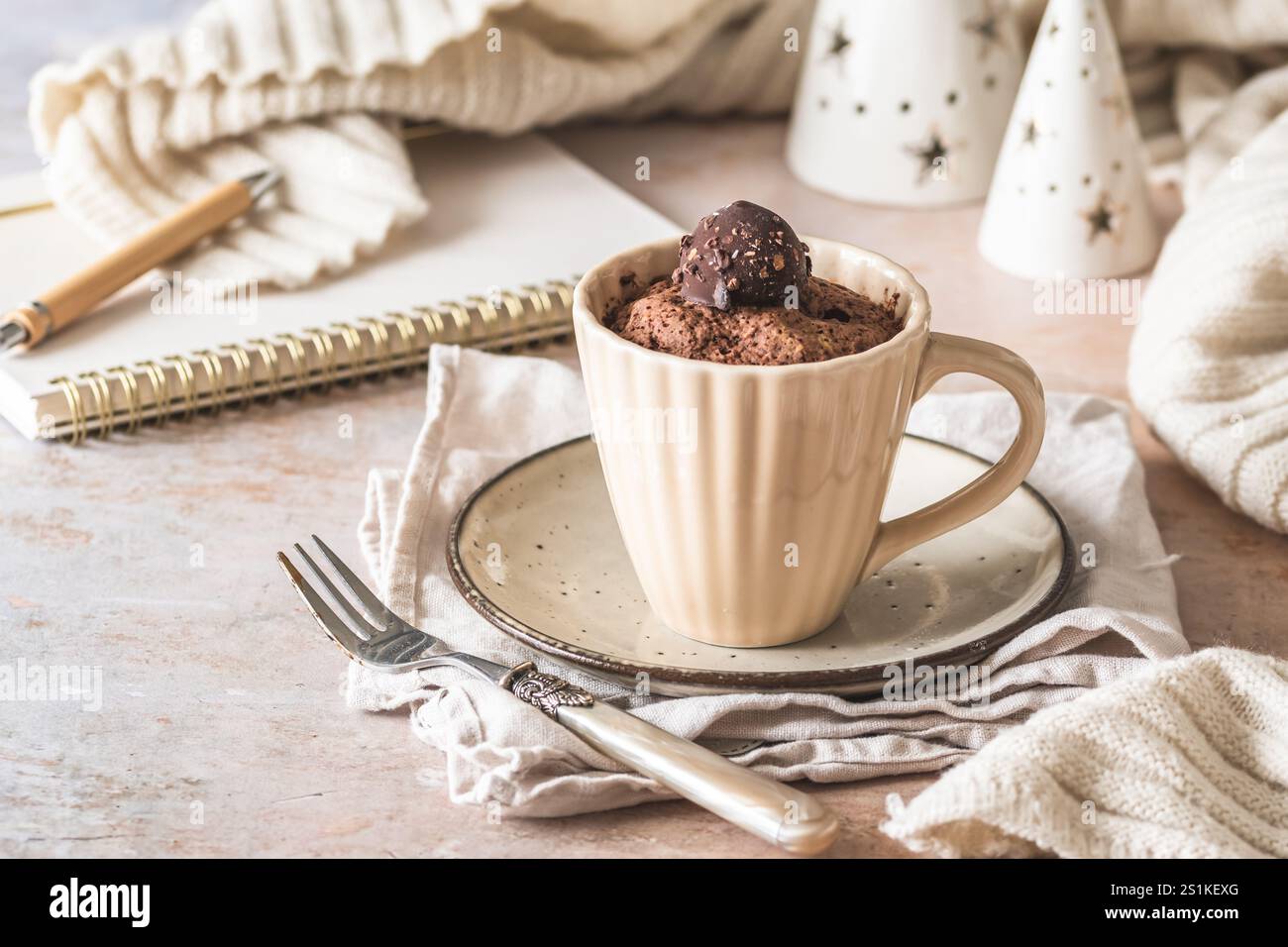 Schokoladentasse Kuchen mit Praline-Topping auf cremeweißem, gemütlichem Hintergrund Stockfoto