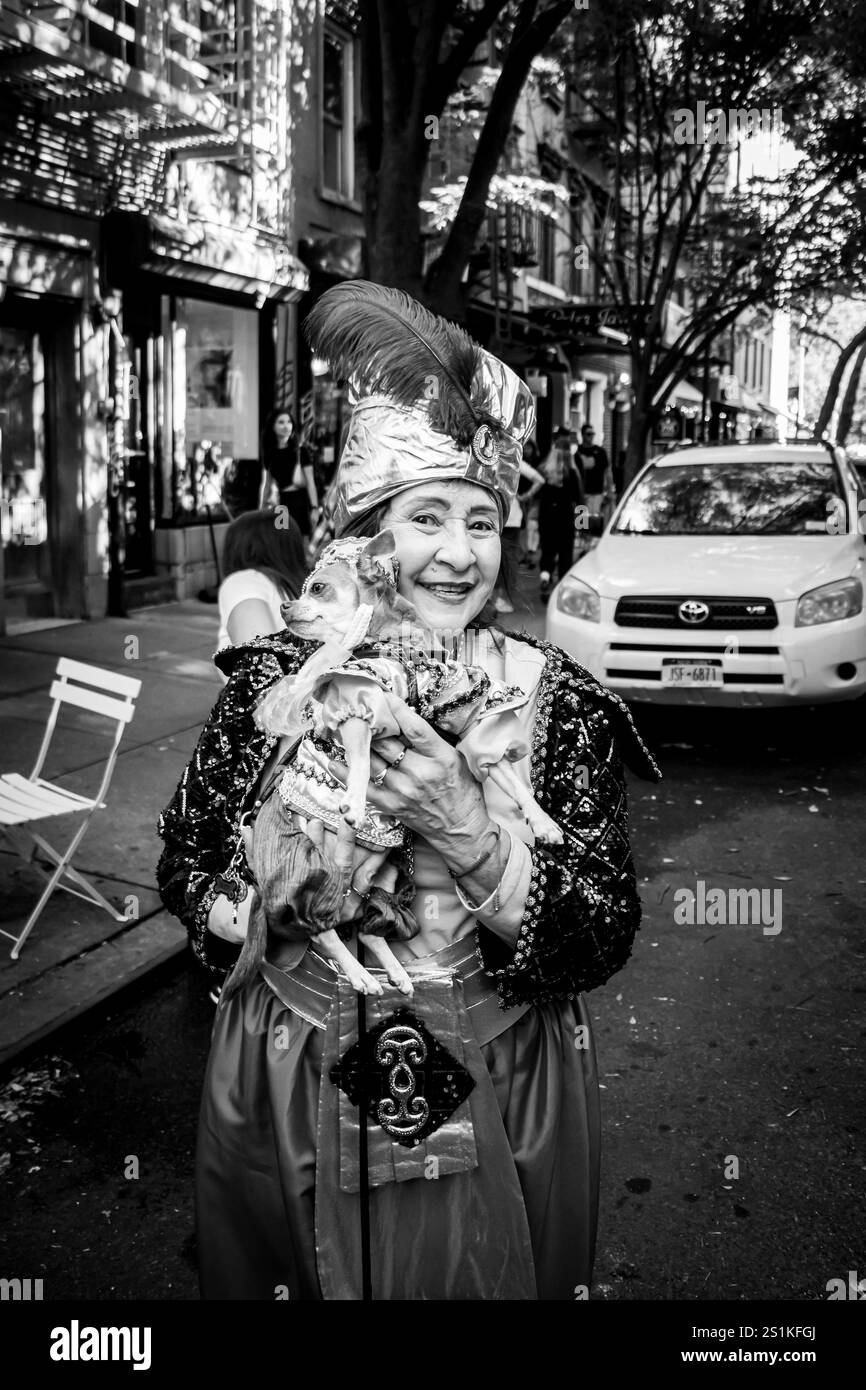 Ältere asiatische Frau in schickem Kleid mit kostümiertem Hund in Tompkins Square Halloween Dog Parade 2024 manhattan New york City USA Stockfoto