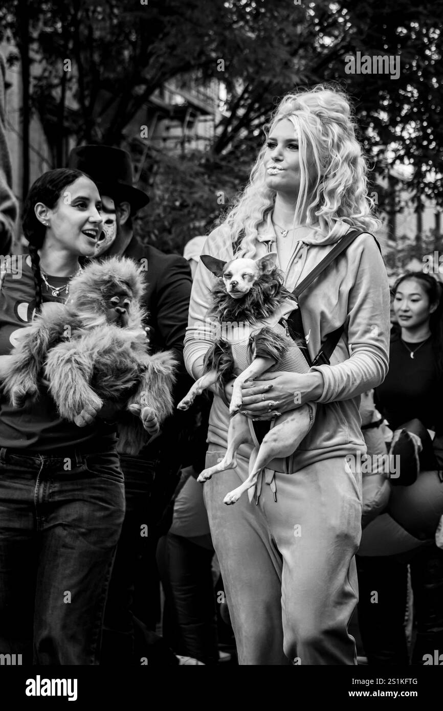 2 Frauen mit einem kleinen Hund im Trachtengeschirr in lebendiger urbaner Umgebung Tompkins Square Halloween Dog Parade manhattan New york usa Stockfoto