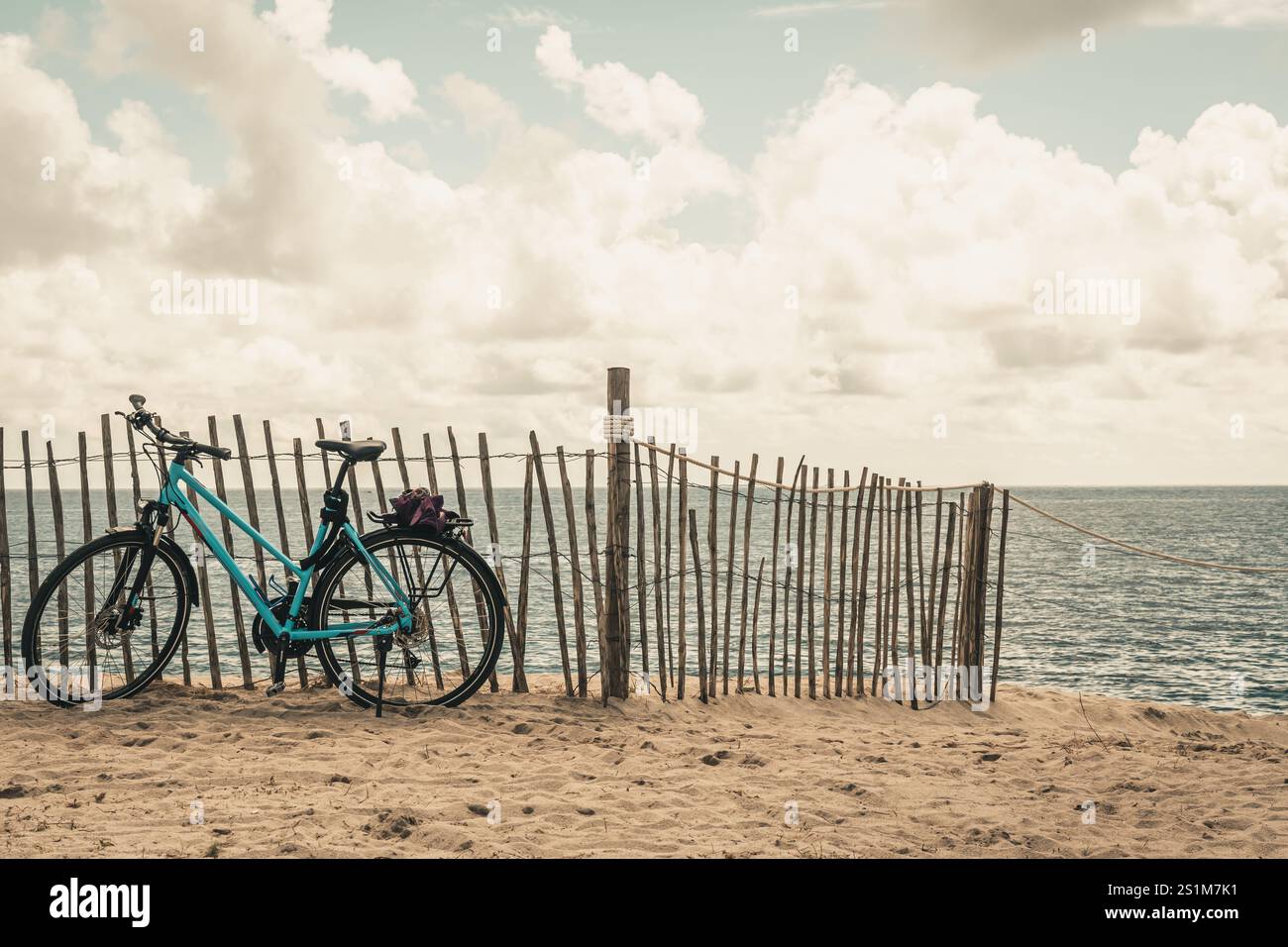 Das Fahrrad lehnt sich an einen Pfahlzaun am Strand Stockfoto