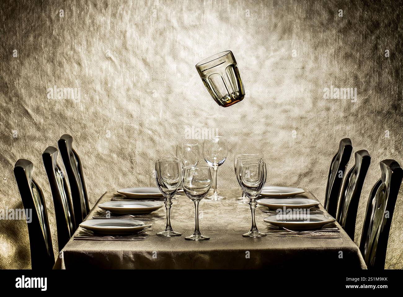 ABENDESSEN FÜR UNSICHTBARE: Ein Glas schwingt über einem voll vorbereiteten Esstisch. Stockfoto
