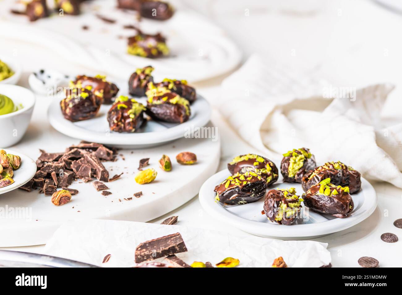 Datteln gefüllt mit knuspriger Pistaziencreme und bedeckt mit Schokolade, Dubai Schokoladendaten, weißer Hintergrund. Nach Zutaten angeordnet. Stockfoto