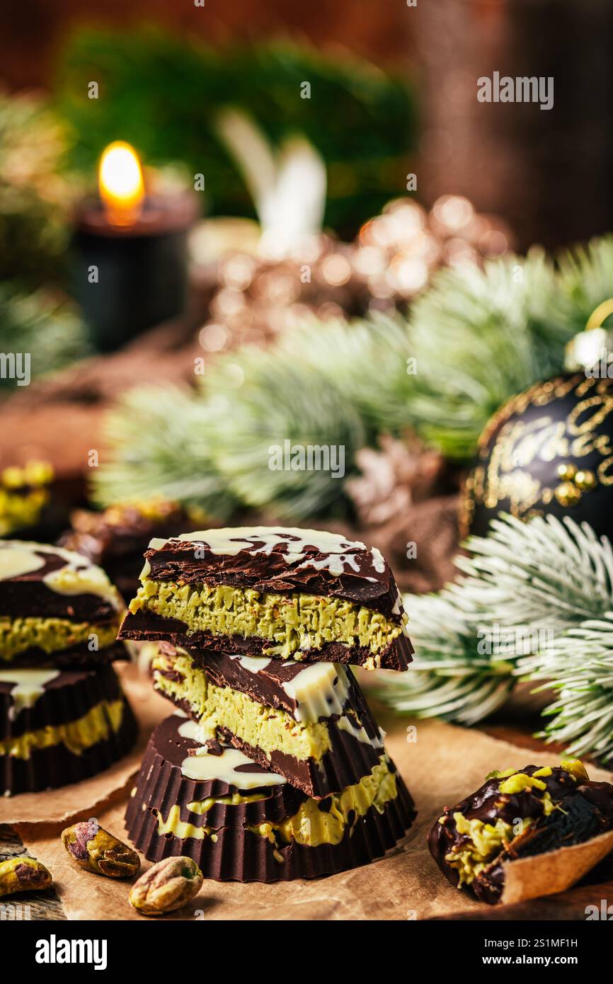 Trendige hausgemachte Dubai Schokoladenpralinen, Schokolade gefüllt mit knuspriger Pistaziencreme, auf hölzernem Hintergrund, dekoriert für weihnachten, vertikal Stockfoto