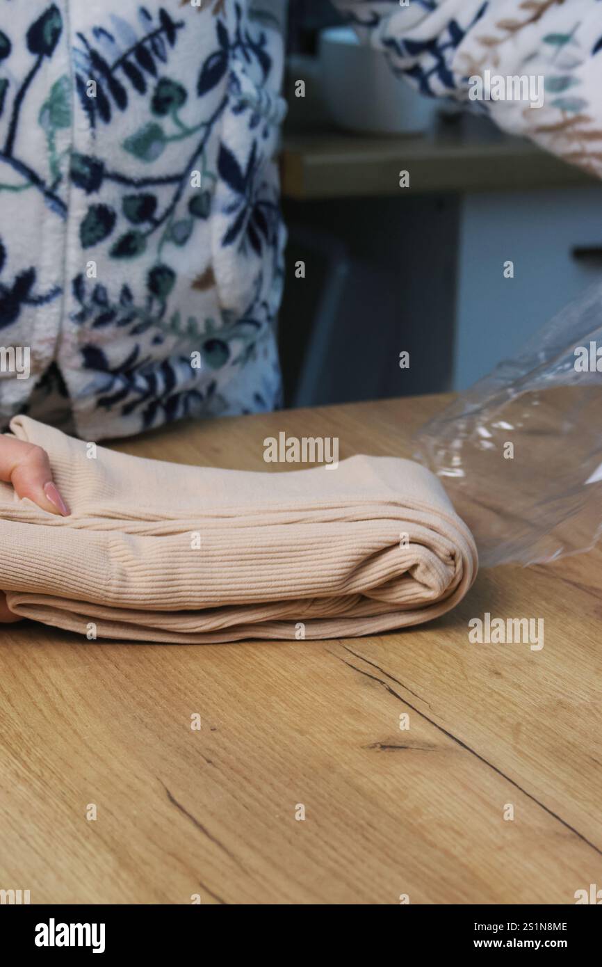 Eine Frau entpackt einen Kauf von einem Marktplatz. Gerippte Thermo-Leggings mit Fleecefutter. Sie nimmt sie aus der Verpackung. Stockfoto