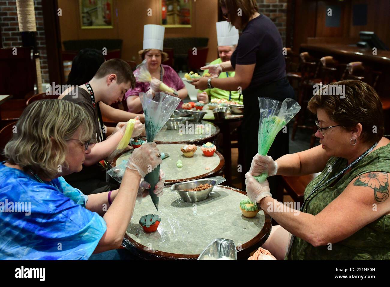 Fort Lauderdale, FL USA - 27. November 2017: Frauen, die Kuchen in der Sprinkle Time Cupcake Decorating Class an Bord eines Kreuzfahrtschiffs der Royal Caribbean gießen. Stockfoto