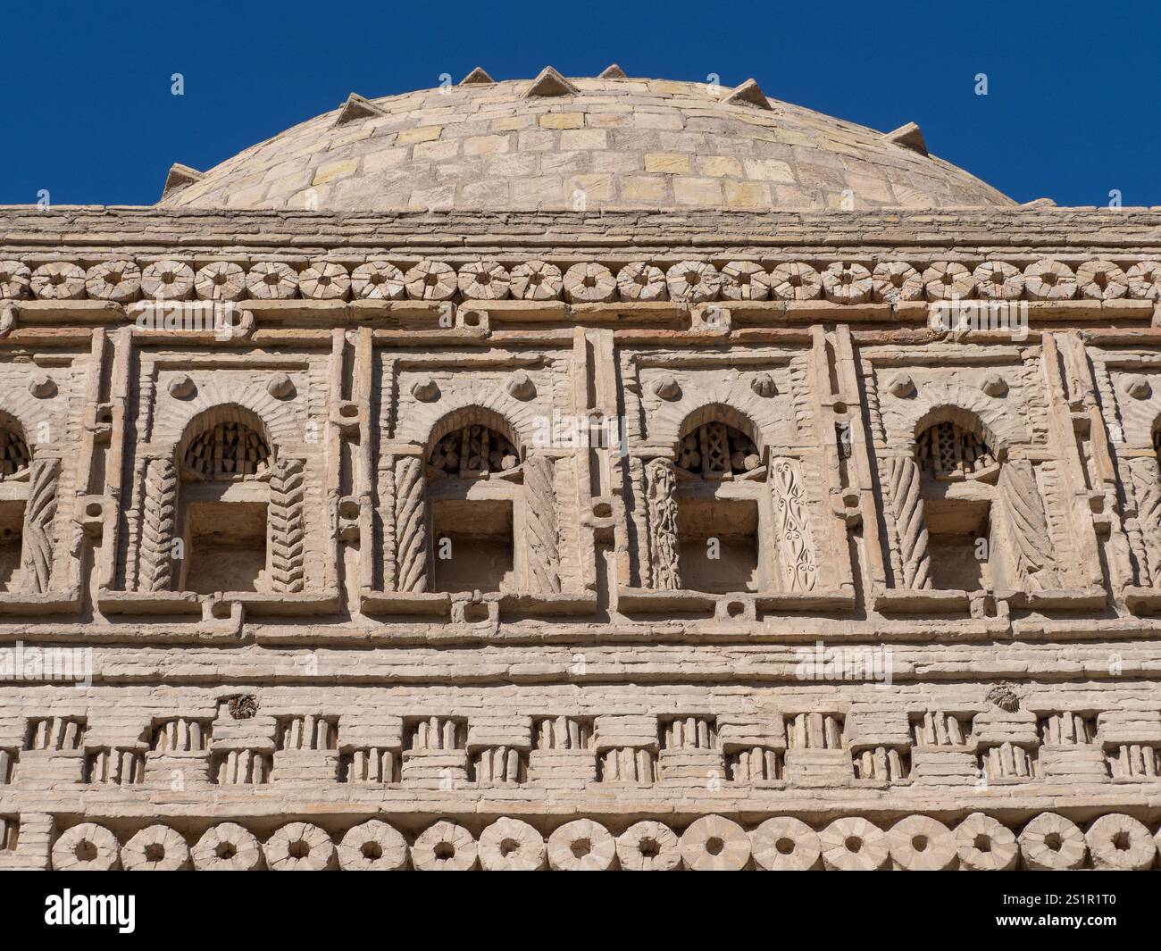 Nahaufnahme des oberen Teils der Ziegelkuppel und der Fassade mit Mustern und gebogenen Nischen des Mausoleums von Ismail Samani in Buchara, Usbekistan. Stockfoto