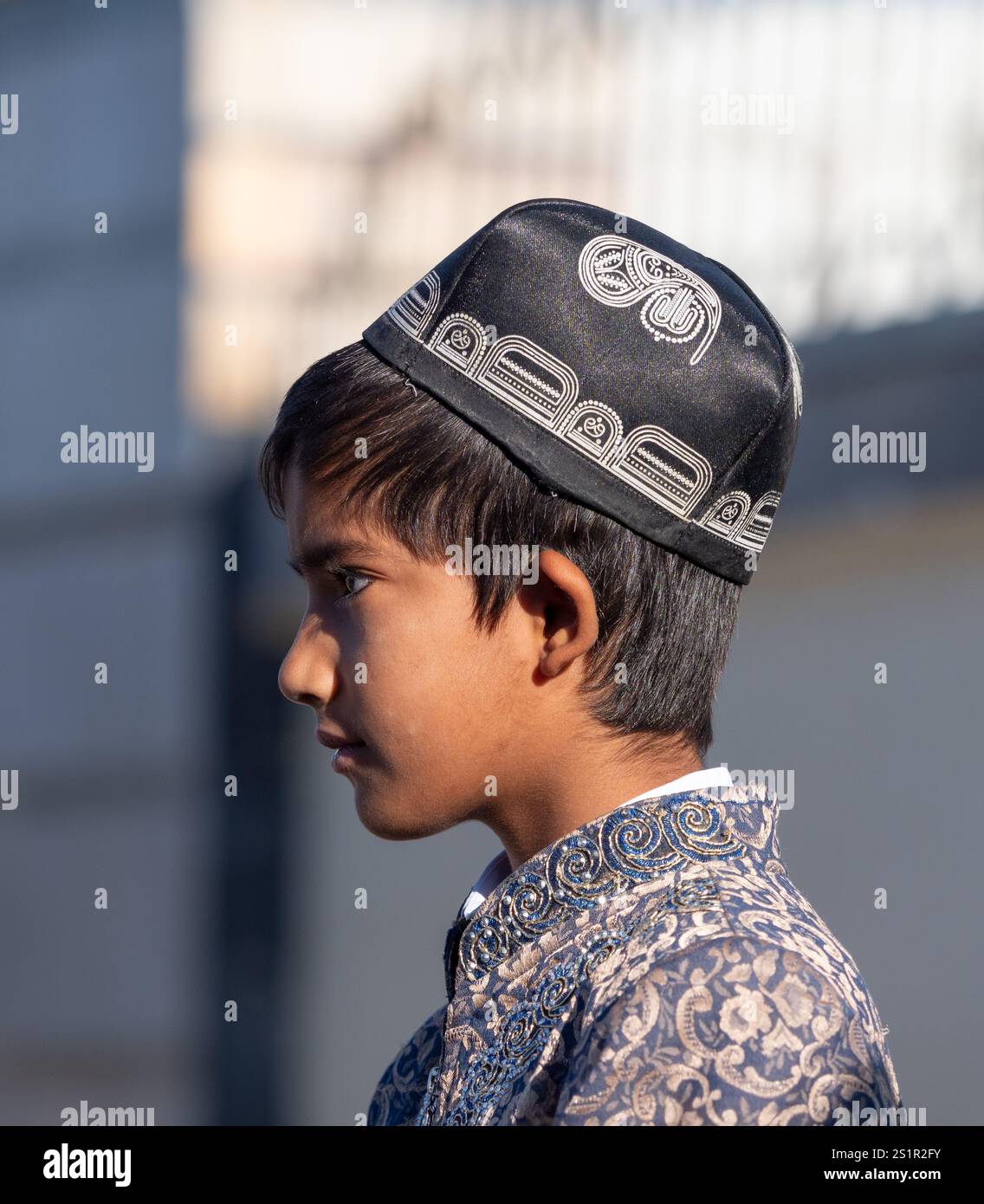 Usbekistanischer Junge mit traditioneller Kleidung und einer Totenkopfkappe oder einem Doppi. Er ist Teil einer Unterhaltungstruppe, die Zugreisende nach Buchara empfängt. Stockfoto