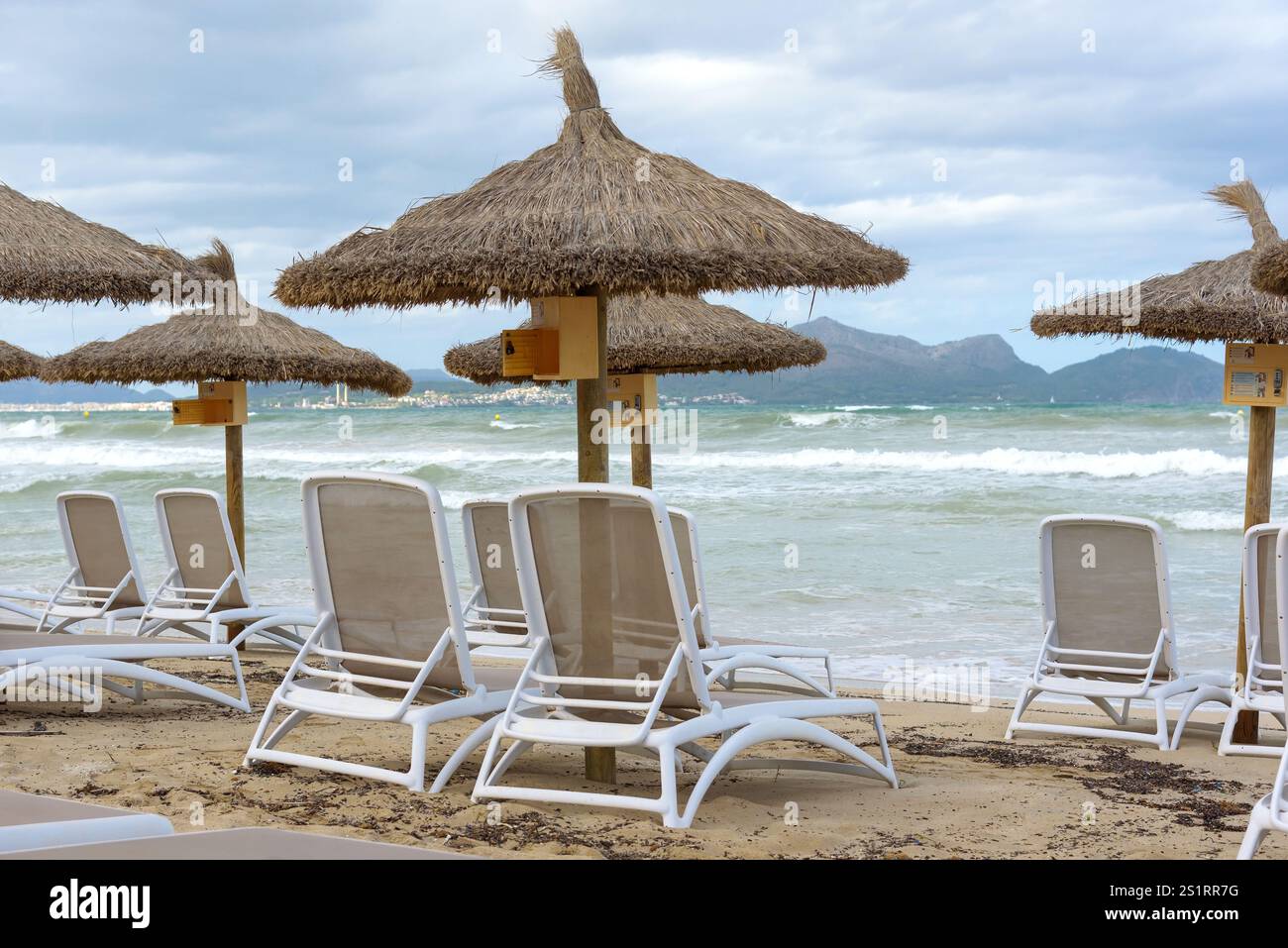 Strohschirme und Sonnenliegen am sonnigen Strand in Can Picafort auf Mallorca. Balearen, Spanien Stockfoto