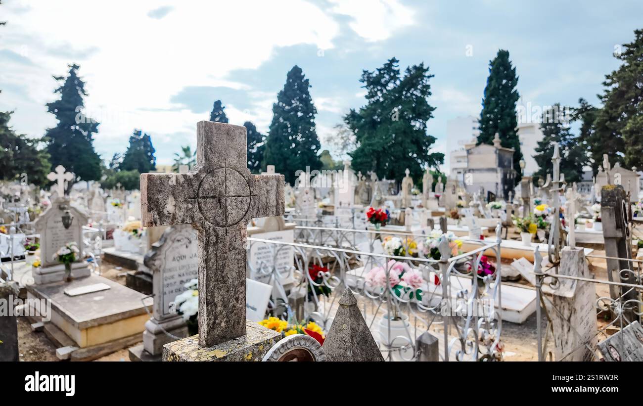 Eine Tagesszene auf einem Friedhof mit einem Kreuz auf einem Grabstein, umgeben von anderen Gräbern Stockfoto