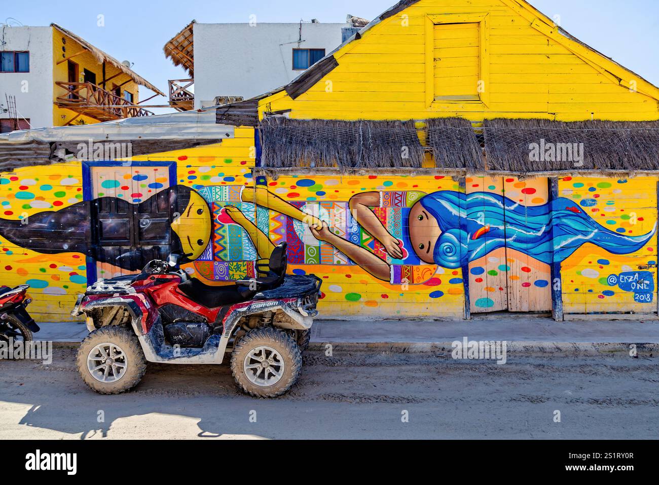 Buntes Street Art Mural auf einem gelben Gebäude mit Quad Bikes in Foreground, Isla Holbox, Mexiko Stockfoto