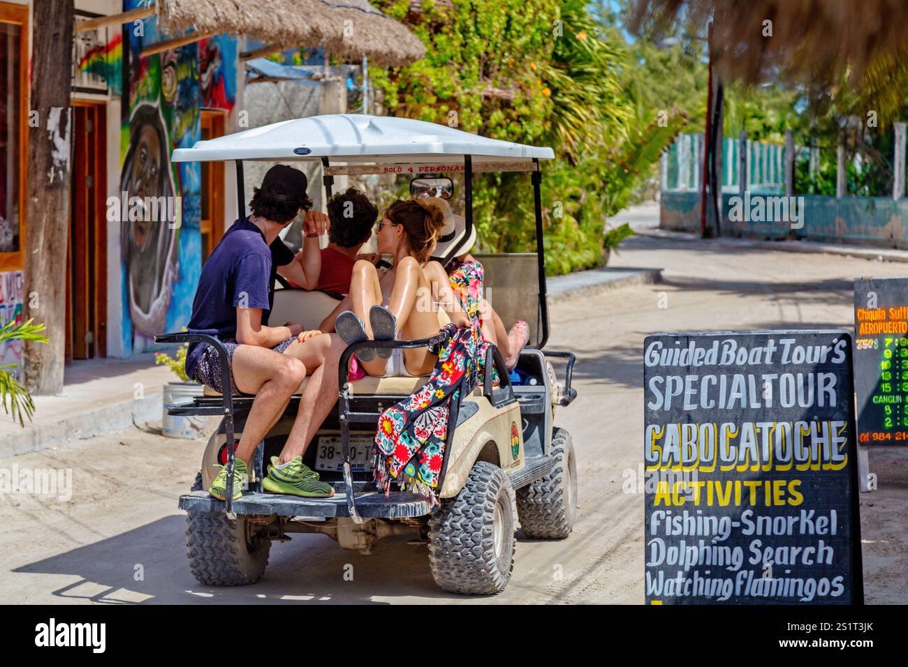 Gruppe von Touristen, die ein malerisches Küstenziel mit dem Golfwagen erkunden, Isla Holbox, Mexiko Stockfoto