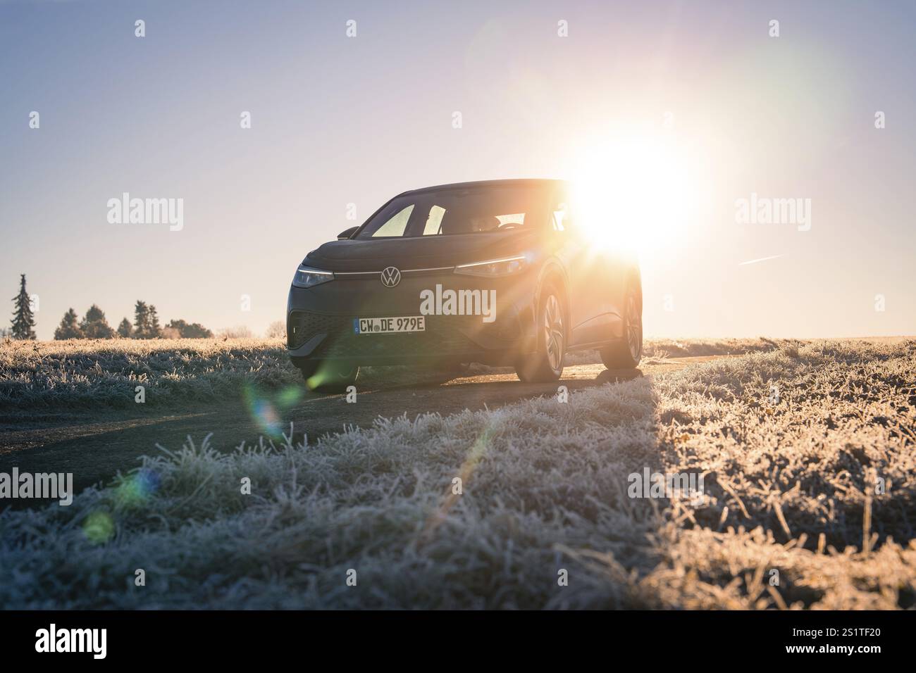 Ein Auto parkt im Winter auf einem frostigen Feld, die Sonne scheint intensiv im Hintergrund, Carsharing, Elektroauto, Volkswagen ID 5, Gechingen, Hecken u Stockfoto