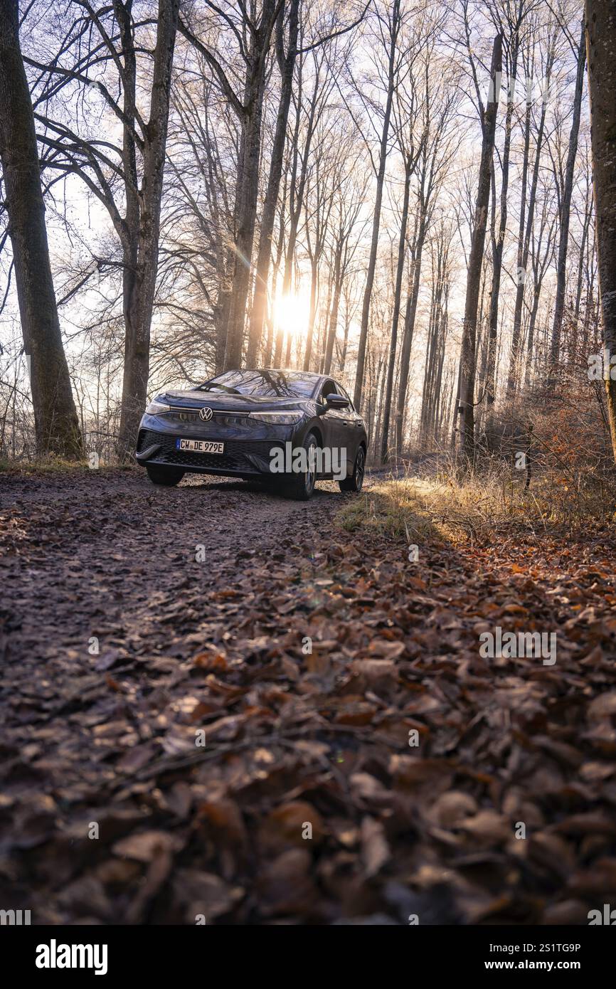 Ein Auto aus einer niedrigen Perspektive auf einem Waldweg im Sonnenlicht, Car Sharing, Elektroauto, Volkswagen ID 5, Gechingen, Region Hecken und Gaeu, Black Fo Stockfoto