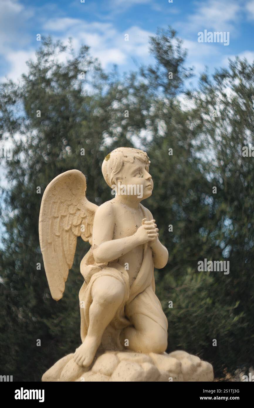 Statue eines Engels mit Flügeln, der zum Himmel blickt und betet Stockfoto