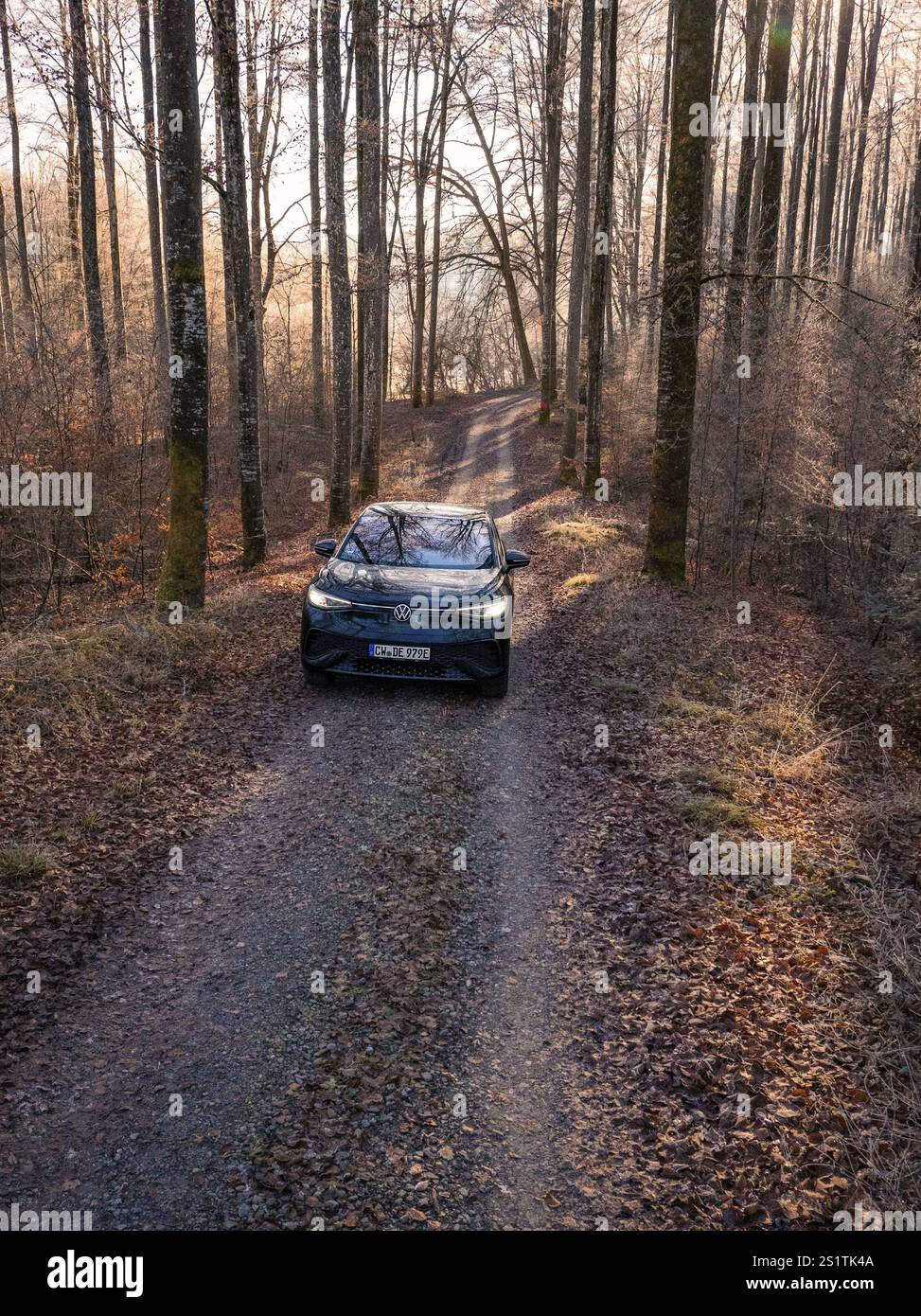 Ein Auto auf einem schmalen Waldweg, von Sonnenlicht überflutet, im Herbst, Carsharing, Elektroauto, Volkswagen ID 5, Gechingen, Region Hecken und Gaeu, Schwarz Stockfoto